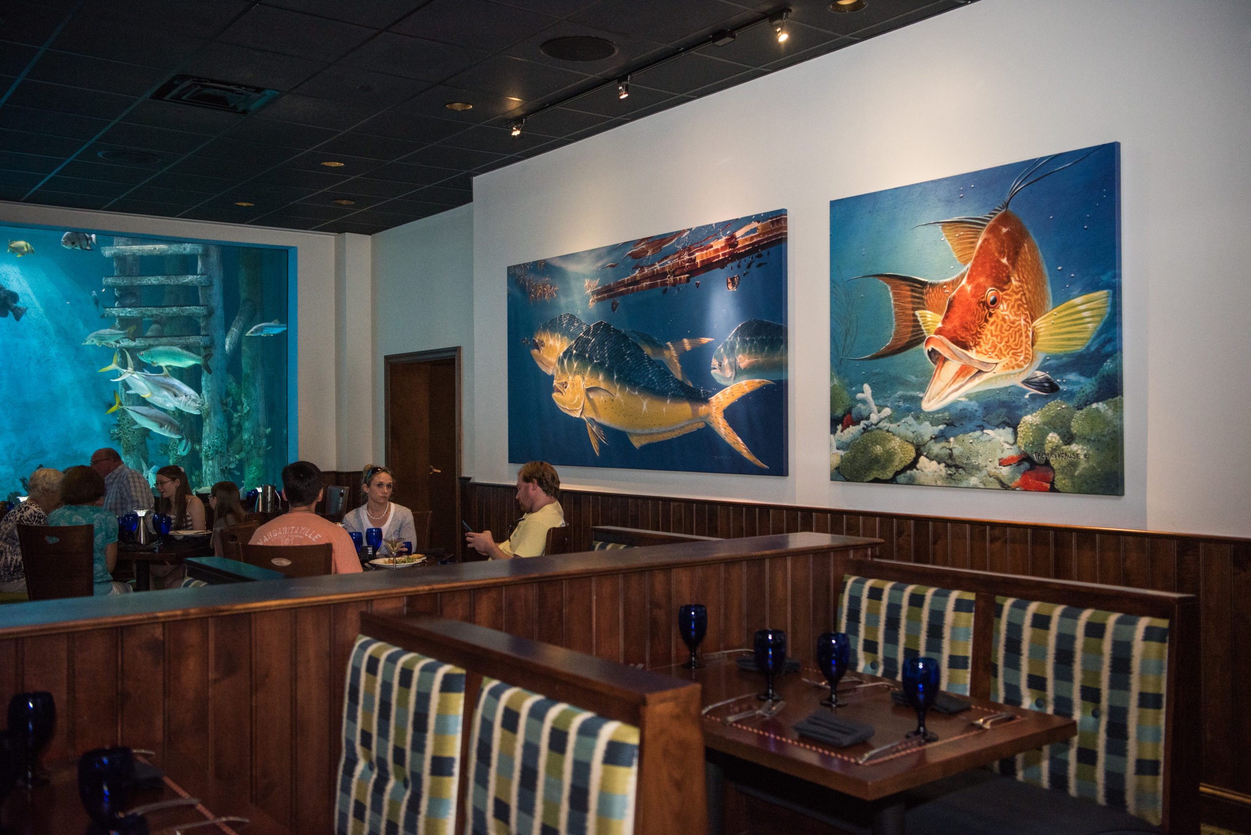 Inside of a sit-down restaurant is a poster display of large fishes swimming in the ocean