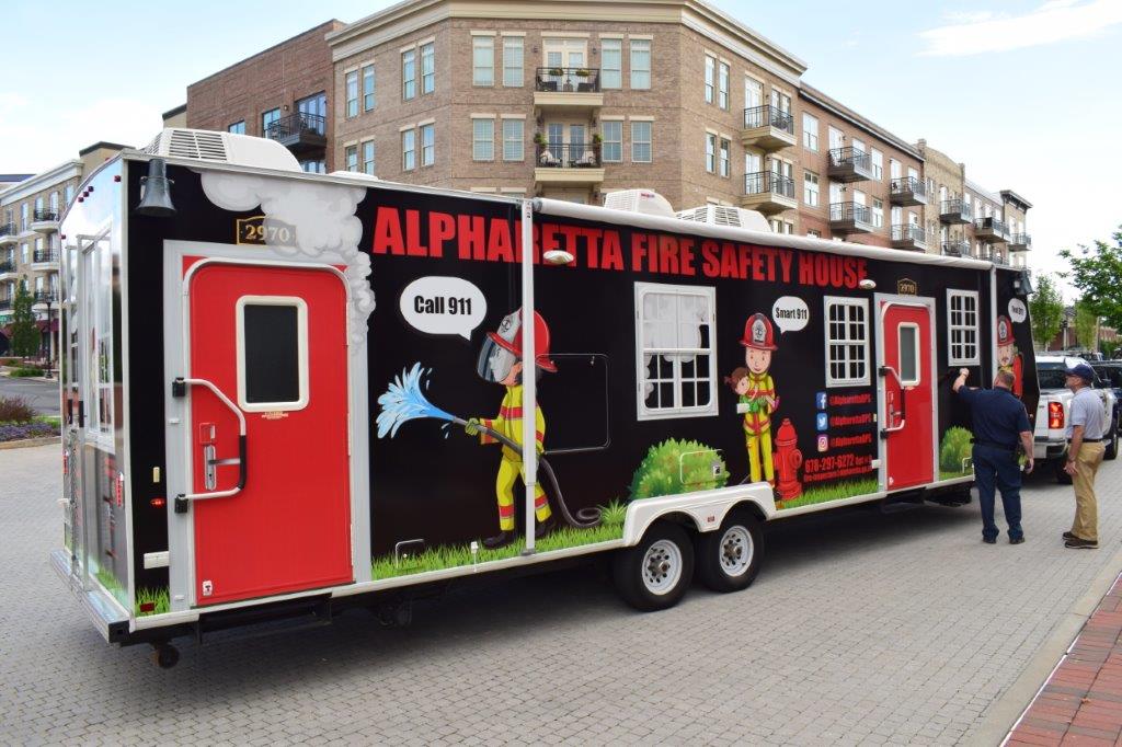two men standing in front of large trailer hitch for alpharetta fire safety house