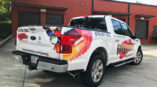 back of white ford pickup truck with vehicle wrap that reads 