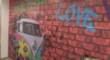 Printed wall of spray painted bricks and rainbow Volkswagen van 