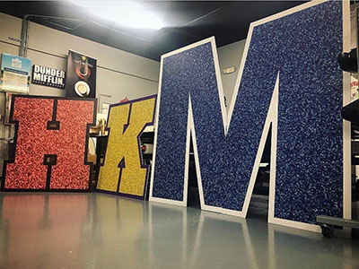 Big multi-colored graphics of the letters H K & M