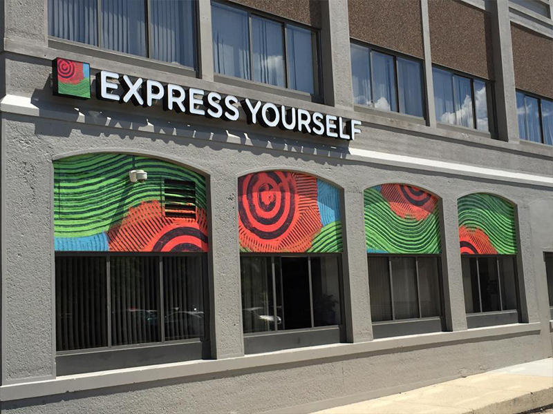 Express Yourself blue, green, and red geometric print over windows 
