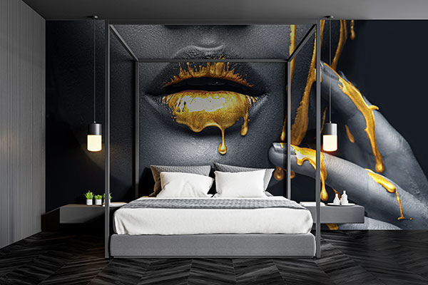 golden paint over a face wall mural behind a bed 