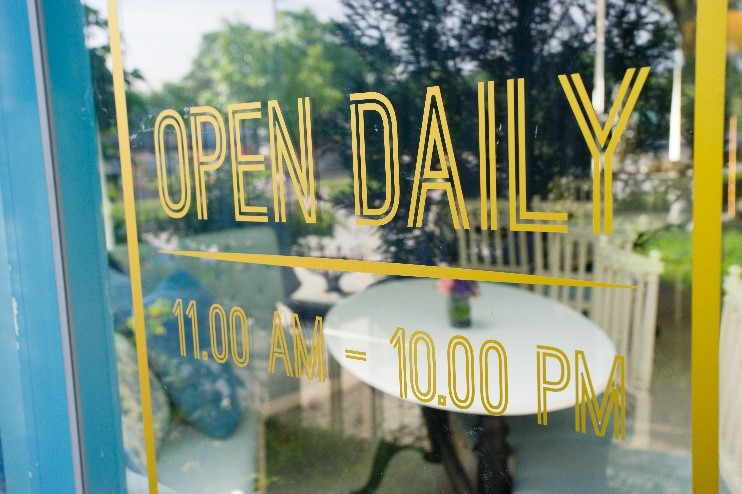 Opening times printed on window with vinyl lettering