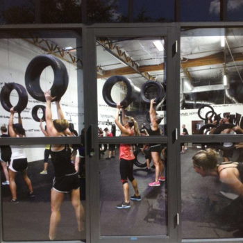 Window graphics of an exercise class where woman are lifting tires.