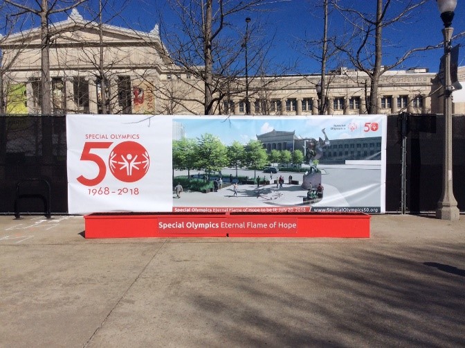 A custom graphic banner for the special olympics displayed on a fence