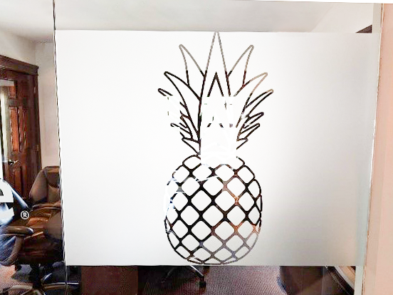 A frosted glass window with a picture of a pineapple etched into the glass