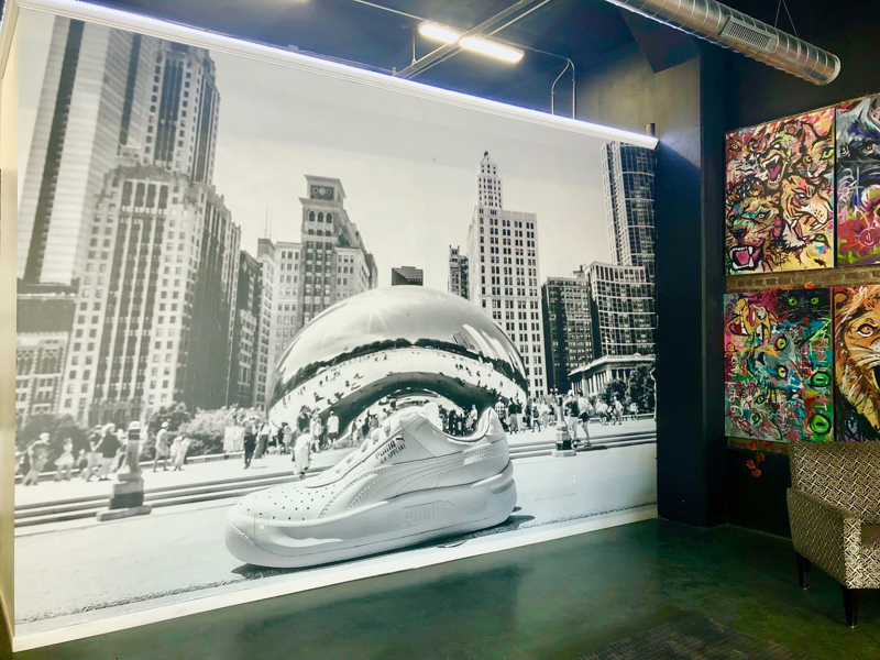 A large custom wall covering of a sneaker in front a city background on display in a store