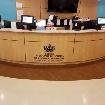 Acrylic wall sign with logo and text on curved reception desk in Chicago Downtown.