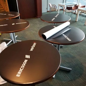 Round vinyl table wraps with logos applied on multiple tables in Chicago Downtown.