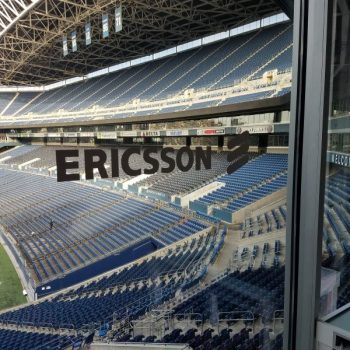 Window graphic decal with bold lettering on glass overlooking empty stadium seats in Chicago