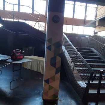 Column wrap with geometric pattern signage in an industrial space near a staircase in Chicago