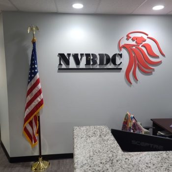 Black and red acrylic wall sign with eagle logo mounted on gray wall in Chicago Downtown office.