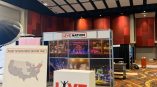 Live Nation Special Events trade show booth inside a convention hall, featuring branded signage, photo panels of concerts, and a white display counter on a patterned carpet floor.