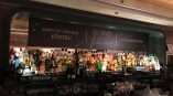 Large printed vinyl banner sign above a bar with liquor bottles in Chicago Downtown.