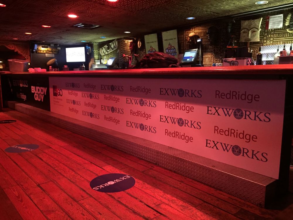 Event vinyl banner attached to a bar front with floor decals in Chicago Downtown.