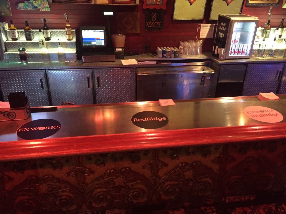 Metal bar counter with circular vinyl decals and diamond plate cabinet doors in Chicago Downtown.