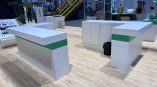 White modular trade show counters with green accent panels on wood floor in Chicago Downtown.