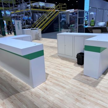 White modular trade show counters with green accent panels on wood floor in Chicago Downtown.