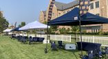 Outdoor feather flags and fabric banners displayed with pop-up tents on grass in Chicago Downtown.