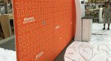 Curved fabric tradeshow display with orange graphic and white icons in Chicago Downtown.