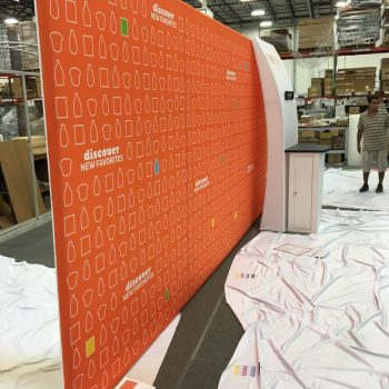 Curved fabric tradeshow display with orange graphic and white icons in Chicago Downtown.