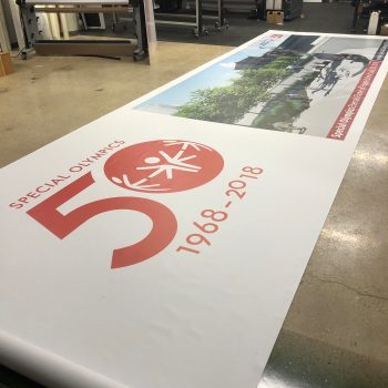 Large vinyl banner with printed graphics and text laid out on a workshop floor in Chicago Downtown.
