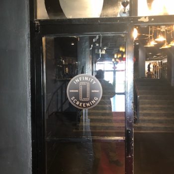 Circular window decal graphic on glass door with black metal frame in Chicago Downtown.