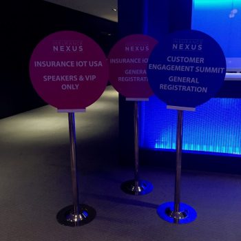 Three round freestanding event signs on metal poles with bases inside a building in Chicago