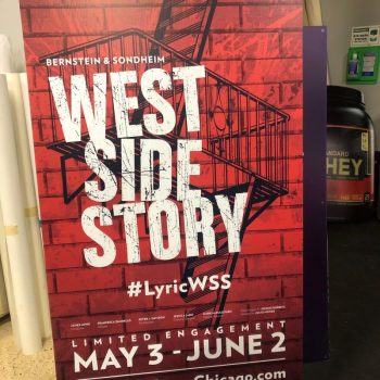 Vertical red promotional poster for West Side Story featuring bold white lettering, a fire escape graphic