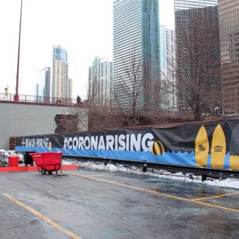 Large outdoor vinyl event banner with surfboard graphics installed on fence in Chicago Downtown.