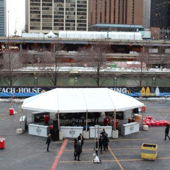 Outdoor event tent with branded vinyl banners and string lights in Chicago Downtown.