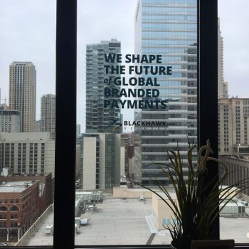 Window decal signage with bold text and logo on glass overlooking Chicago Downtown.