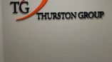 Acrylic wall sign with black and orange lettering mounted on a gray wall in Chicago Downtown.