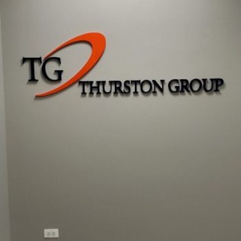 Acrylic wall sign with black and orange lettering mounted on a gray wall in Chicago Downtown.