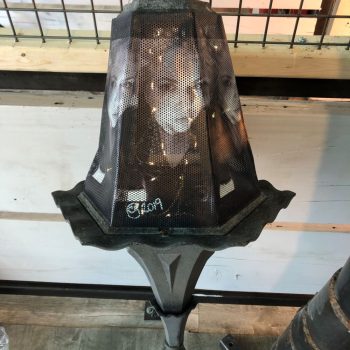 Artistic perforated metal street lamp cover with printed faces in Chicago Downtown.