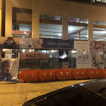 Construction site fence mesh banners and orange plastic barriers at night in Chicago Downtown.