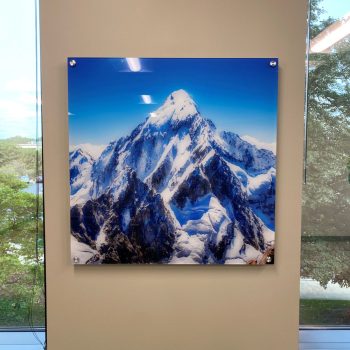 Mounted acrylic wall sign with a snow-covered mountain image between windows in Chicago Downtown.