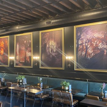 Four large framed canvas wall signs with forest and fantasy scenes above dining tables in Chicago