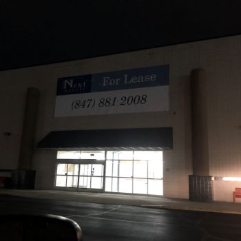 Large vinyl banner mounted above the entrance of a commercial building in Chicago Downtown.