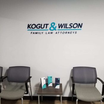 Acrylic wall sign with black and teal lettering mounted above chairs in Chicago Downtown office.