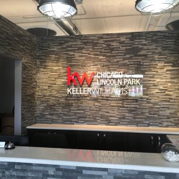 Acrylic wall sign with red and white lettering mounted on a stone wall in Chicago Downtown.