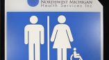 Curved blue and white ADA restroom sign with braille and symbols in Chicago Downtown.