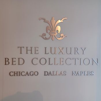 Brushed metal wall sign with decorative emblem and text mounted on white wall in Chicago Downtown.