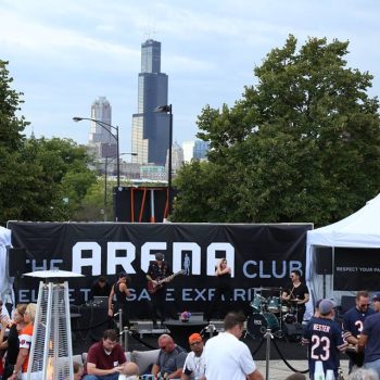 Large vinyl event banner with stage setup and tents in Chicago Downtown park.