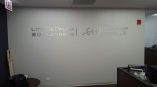 Metal wall sign with brushed silver letters mounted on gray wall in Chicago Downtown office.