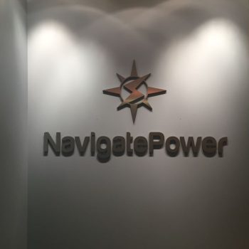 Metal wall sign with logo and text mounted on white wall in Chicago Downtown office.