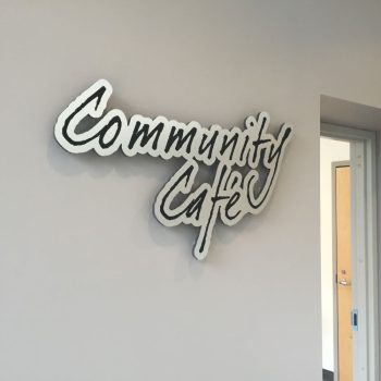 Custom cut metal wall sign with black and white lettering mounted indoors in Chicago Downtown.