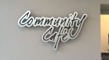 Cut metal wall sign with script lettering mounted on gray wall in Chicago Downtown.
