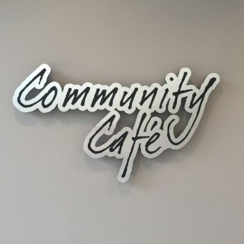 Cut metal wall sign with script lettering mounted on gray wall in Chicago Downtown.